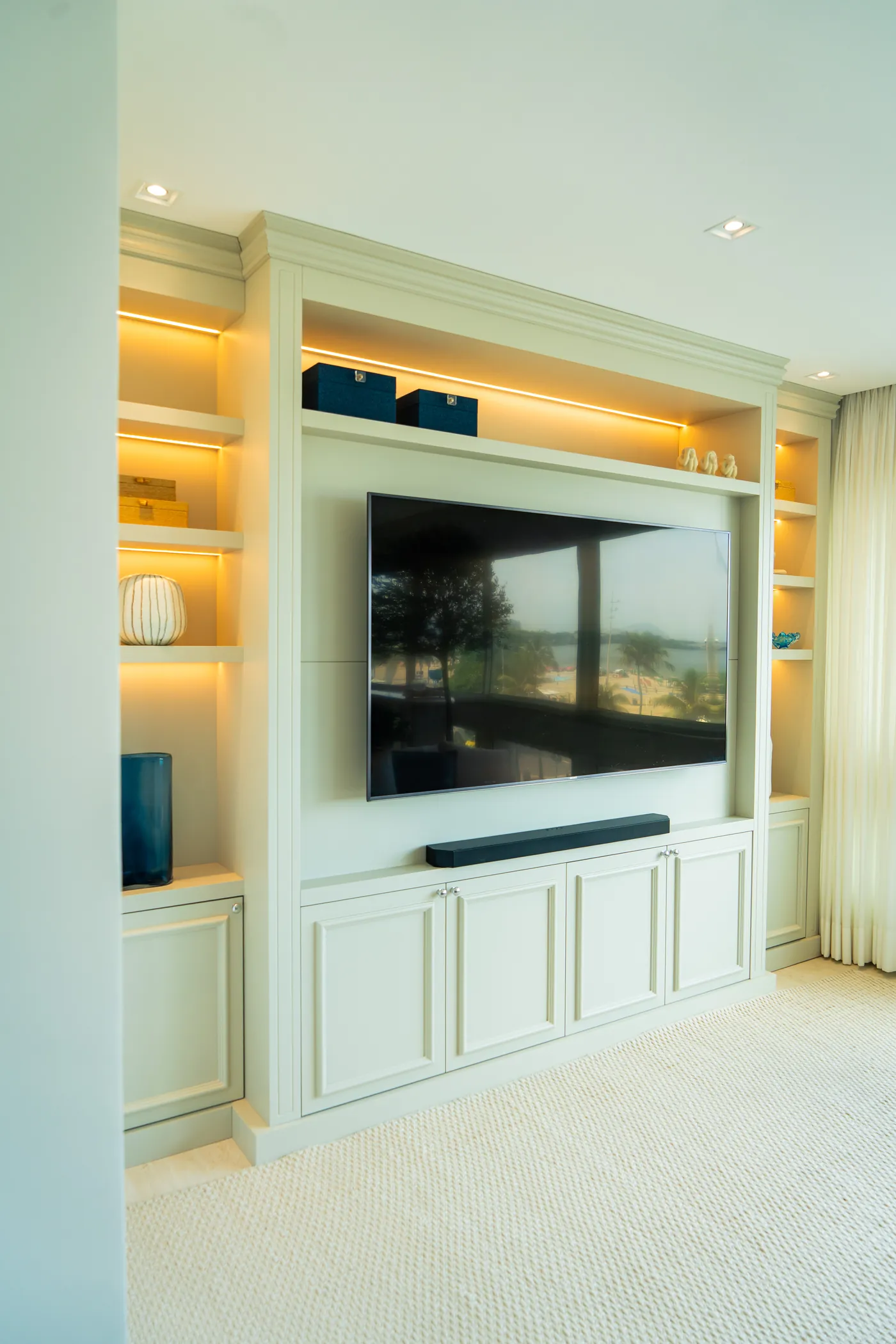 Painel de TV com estante lacada e nichos iluminados, executados sob medida